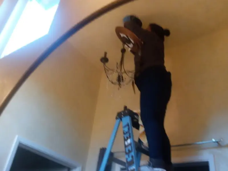 Electrician installing a chandelier in a Anderson residence